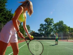拉罗克当泰龙Vacances en Provence en mobil home的女子在网球场上打网球和球拍