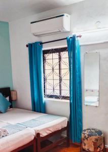 巴加Baga Beach Paradise的客房设有两张床和一扇带蓝色窗帘的窗户。