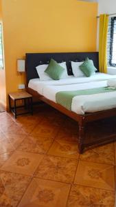 巴加Baga Beach Paradise的一间卧室配有两张带绿色和白色枕头的床