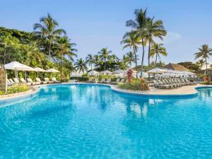丹娜努索菲特斐济温泉度假酒店的度假村的游泳池,配有椅子和遮阳伞