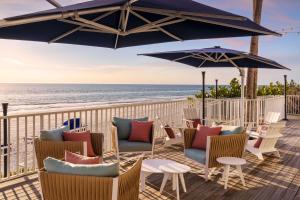 圣徒皮特海滩坦帕湾 - 北雷廷顿海滩希尔顿逸林海滩度假酒店的海滩上带椅子和遮阳伞的甲板