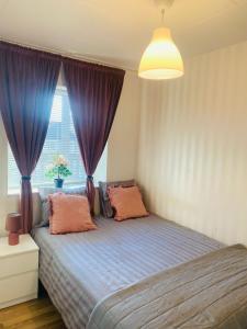 谢莱夫特奥Noah Longstay Skellefteå的一间卧室配有一张带紫色窗帘的床和窗户。