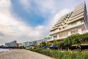 圣玛尔塔Santa Marta Marriott Resort Playa Dormida的海滩旁一座带蓝伞的大型白色建筑