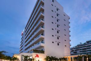 圣玛尔塔Santa Marta Marriott Resort Playa Dormida的一座高大的白色建筑,前面有棕榈树