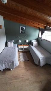 乌斯怀亚Buenavida Guesthouse的一间卧室设有两张床、一张桌子和两个窗户。