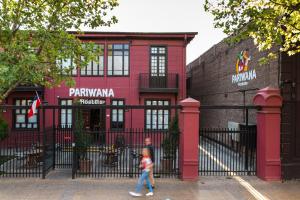 圣地亚哥Pariwana Hostel Santiago的一个小女孩走过红色的建筑