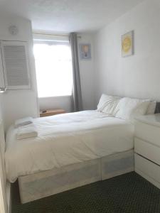 珀利Cozy One Bed Apartment Near Purley Station的卧室配有一张大白色床和窗户