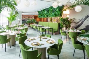 新加坡Capri by Fraser China Square, Singapore的餐厅设有白色的桌子和绿色的椅子