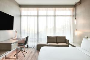 森尼维耳市AC Hotel by Marriott Sunnyvale Moffett Park的酒店客房配有一张床、一张书桌和一张沙发。