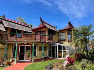 HueloMaui Eco Retreat的带阳台的黄色房屋和棕榈树