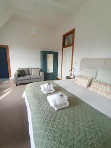 提马鲁Kingsdown Manor B&B Timaru的一间卧室配有一张大床和毛巾