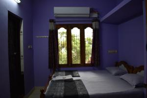 蒂鲁瓦纳马莱Rainbow Guest House的蓝色卧室,配有一张带窗户的床