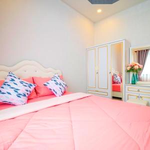 农布BreezyS Pool Villa的卧室配有带枕头的大型粉红色床