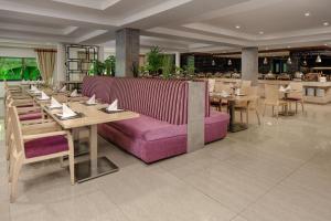 达累斯萨拉姆Delta Hotels by Marriott Dar es Salaam的餐厅设有紫色的沙发和桌椅