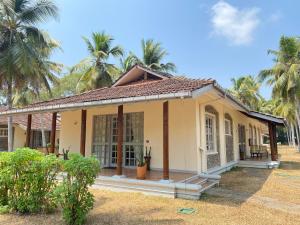尼甘布Tamarind Tree Garden Resort - Katunayake的棕榈树下的小黄色房子