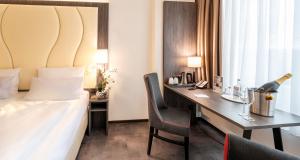 曼海姆Best Western Plaza Hotel Mannheim的酒店客房,配有一张床和一张带一瓶香槟的书桌