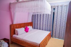 坎帕拉Twin towers hotel的一间卧室配有带白色床单和粉红色枕头的床。