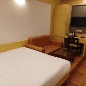 德奥加尔Hotel Taj Akash的酒店客房配有一张床、一把椅子和一张书桌