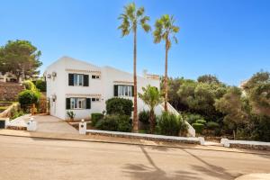 埃斯卡纳特尔Villa Can Palmeras by Villa Plus的棕榈树和街道的白色房子