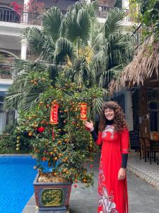 宁平Tam Coc Full House Homestay的站在圣诞树旁边的一个穿着红色衣服的女人