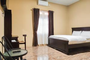 占碑市RedDoorz Syariah near Telanaipura Jambi的卧室配有床、椅子和窗户。