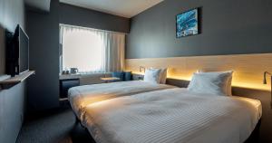 熊本Grids Premium Hotel Kumamoto的酒店客房设有一张大床和一台电视。