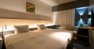 熊本Grids Premium Hotel Kumamoto的一间酒店客房,配有一张白色的床和一张书桌