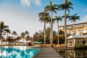 努美阿努美阿子午线度假酒店及Spa的一座带游泳池、棕榈树和大楼的度假村