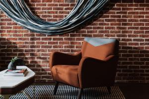 萨凡纳The Alida, Savannah, a Tribute Portfolio Hotel的砖墙旁的棕色椅子