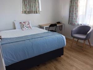 汉密尔顿Melville Guest House near Waikato Hospital的一间卧室配有一张床、一把椅子和一张书桌