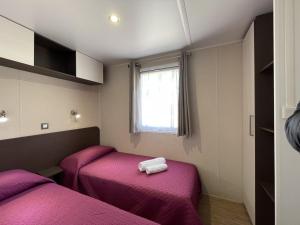 托尔托利Campeggio Villaggio Sos Flores的客房设有两张带紫色床单的床和窗户。