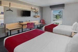 杜兰戈杜兰戈城市快捷酒店的酒店客房设有两张床、一张桌子和一张桌子。