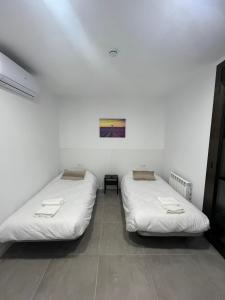 曼雷沙Hostal La Masia的白色墙壁客房的两张床