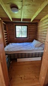 埃斯波Hirsimökki kansallispuistossa的小木屋内的一张小床,设有窗户