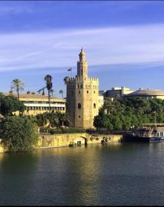 塞维利亚Ritual Sevilla, piedra preciosa的水体旁有钟楼的房子