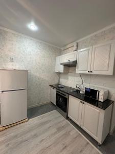 阿拉木图ЖК Ashyq Tobe的厨房配有白色橱柜和白色冰箱。