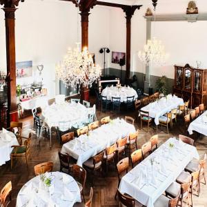 塔廷格Wellenreiter的用餐室配有白色桌椅和吊灯。