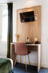 梅斯Hôtel Escurial - Centre Gare的酒店的客房,配有一张桌子,墙上有一台电视机