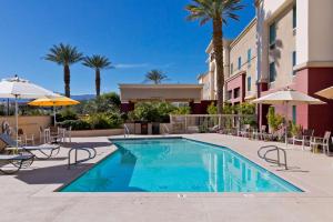 棕榈荒漠汉普顿棕榈沙漠套房酒店的游泳池,带椅子和遮阳伞