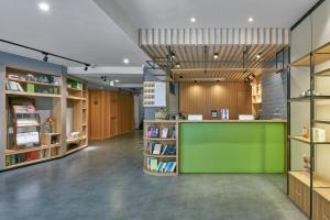 成都成都锦里亚朵轻居酒店的一个带绿色柜台和书架的图书馆