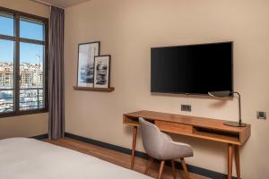 马赛马赛老港口丽笙酒店的酒店客房设有一张桌子和一台墙上的电视