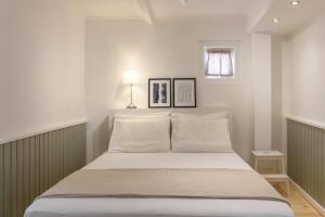 科孚镇Keramidogatos Manos Guest House, Corfu Old Town的一间卧室配有一张带白色床单的床和一扇窗户。