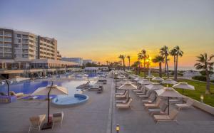 莫纳斯提尔Hilton Skanes Monastir Beach Resort的海滩旁的一组躺椅和遮阳伞