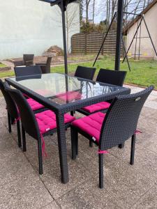 巴伦塔尔Le Refuge de l'Ours的一张带粉红色软垫椅子和遮阳伞的玻璃桌