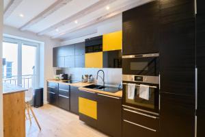 南特LE BLUM COEUR - Hyper Centre Nantes的厨房配有黑色和黄色的橱柜和水槽