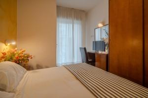 里米尼Hotel Mia的配有一张床、一张书桌和一扇窗户的酒店客房