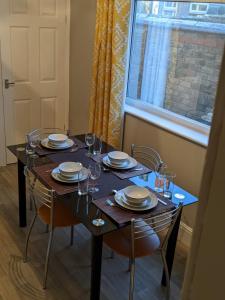 格里姆斯比*Feel at home* 3bed 2bath house Cleethorpes的餐桌,带盘子和玻璃杯,窗户