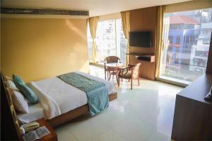 古瓦哈提HOTEL APOLLO GRAND A UNIT OF SATYAM ASSOCIATES的一间卧室配有一张床、一张桌子和一个窗户。