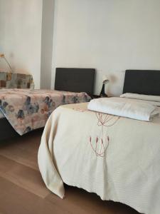 诺瓦拉Bellini Apartment's的一间卧室配有两张床和白色毯子