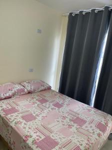 圣若泽-达科罗阿格兰迪Casa 3 Quartos, 2 suites, piscina e sossego的一间卧室配有一张带粉红色棉被的床和一扇窗户